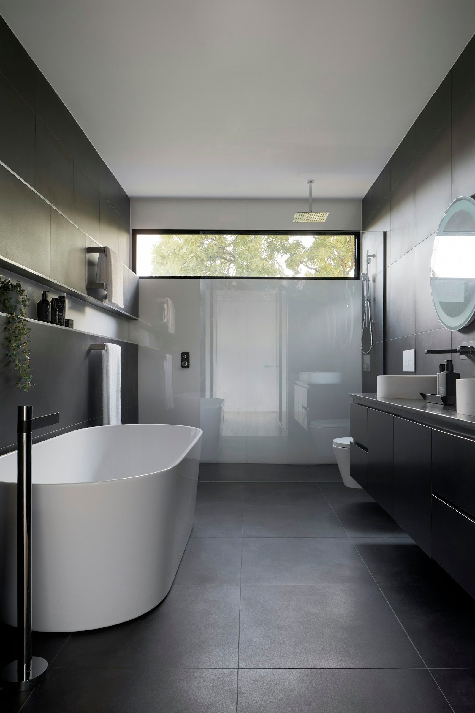 Hochwertiges Designbad mit freistehender Badewanne, dunklen Fliesen und Regendusche