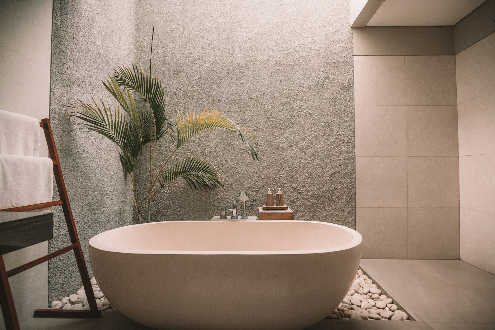 Warm gestaltetes Badezimmer mit ovaler Badewanne, Natursteinen und Naturtönen